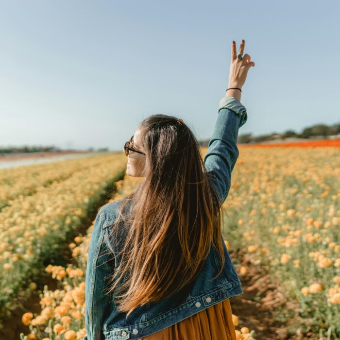 A woman enjoying a sunny day in a vivid yellow flower field in Carlsbad, CA.
